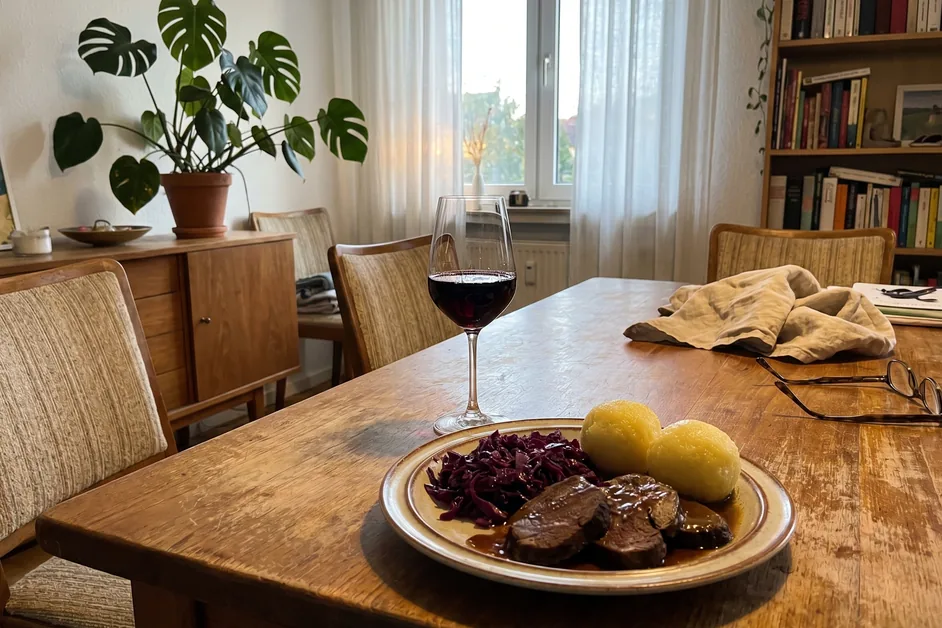 Glas Frühburgunder zu Wildbraten mit Rotkohl und Klößen auf einem Esstisch im modernen Esszimmer