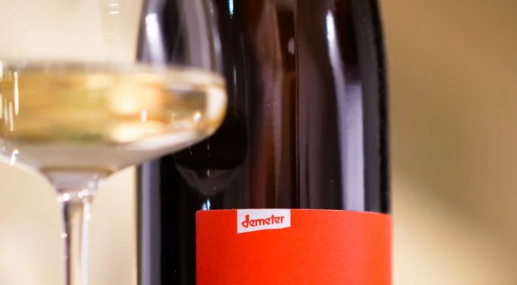 Weißwein im Glas und Demeter-Flasche des Weinguts Kaufmann