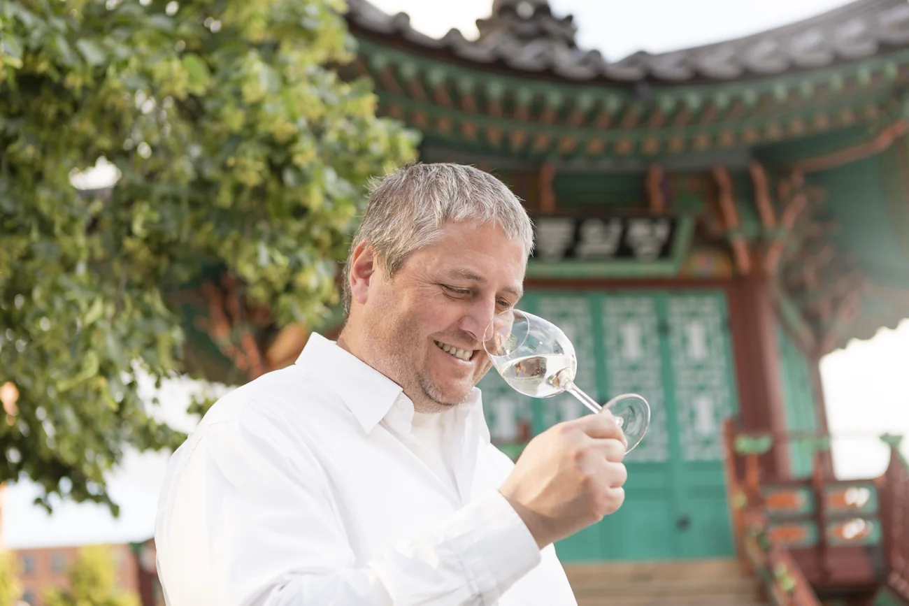 Robert Wurm mit einem Glas Riesling vor koreanischer Tempelkulisse