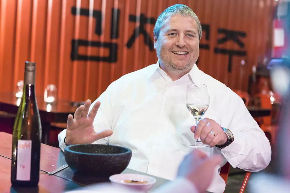 Robert Wurm mit Weinglas vor koreanischer Kulisse, zwei Welten, eine Philosophie